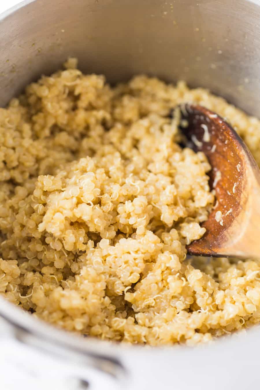A bowl of quinoa with a wooden spoon in it