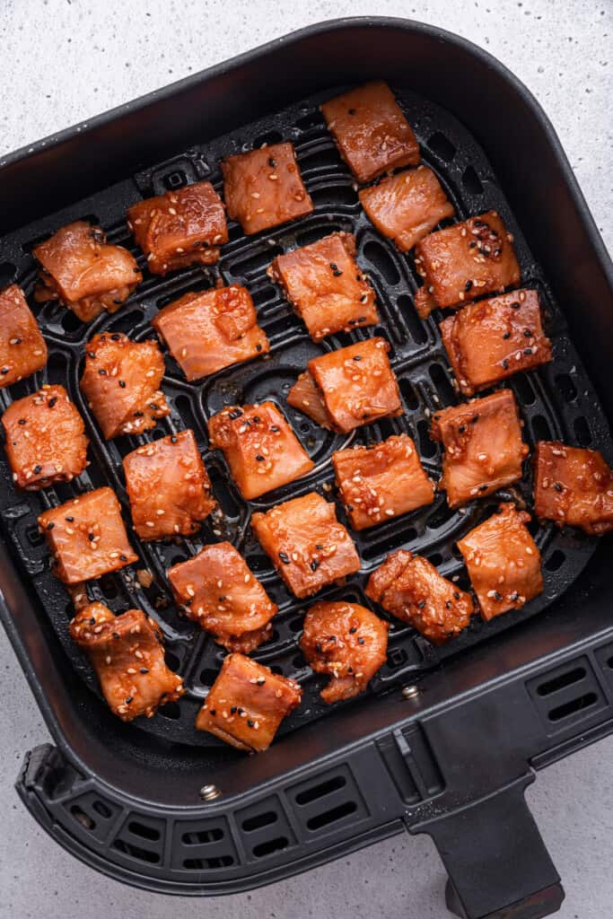 Overhead view of salmon bites added to air fryer basket