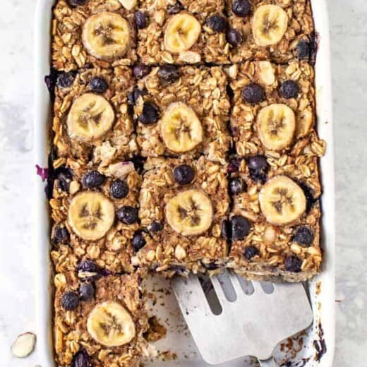 Overhead view of banana blueberry baked oatmeal in baking dish with spatula