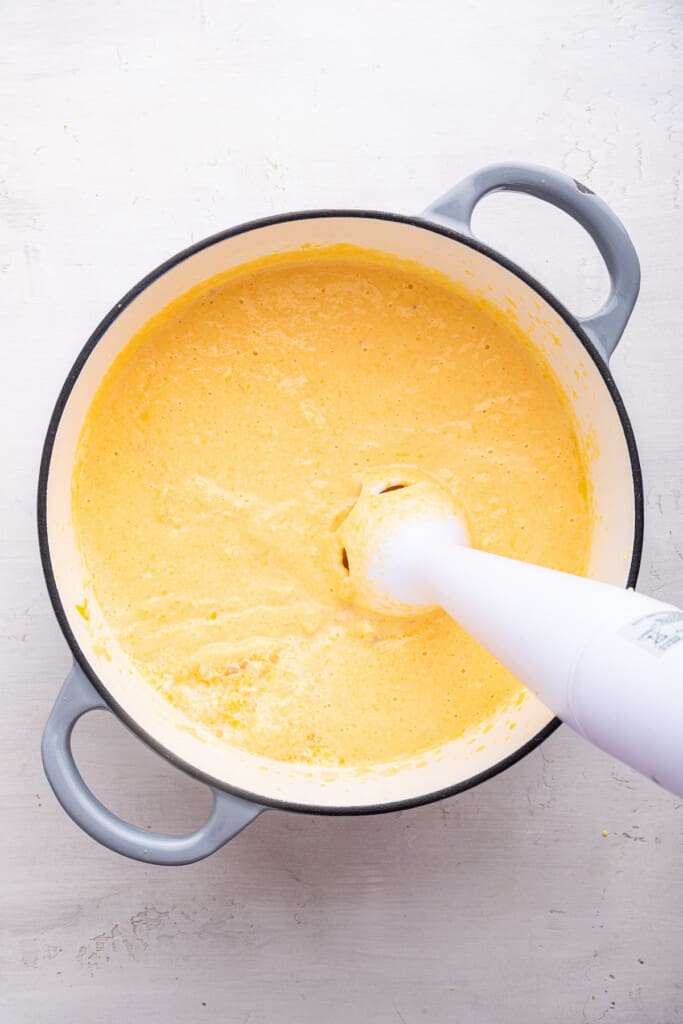 Overhead view of immersion blender pureeing butternut squash cheese sauce