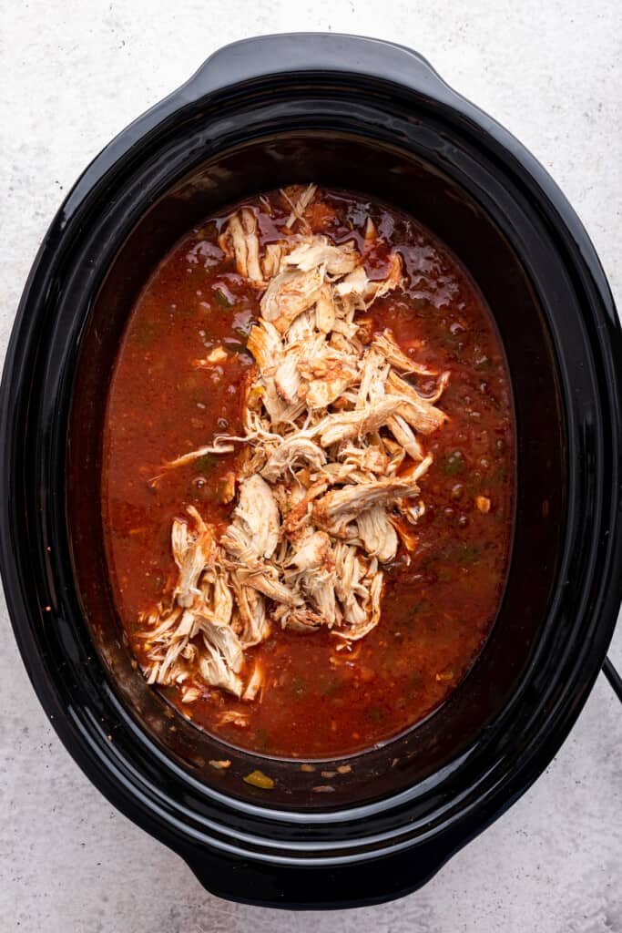 Overhead view of shredded chicken added back to slow cooker