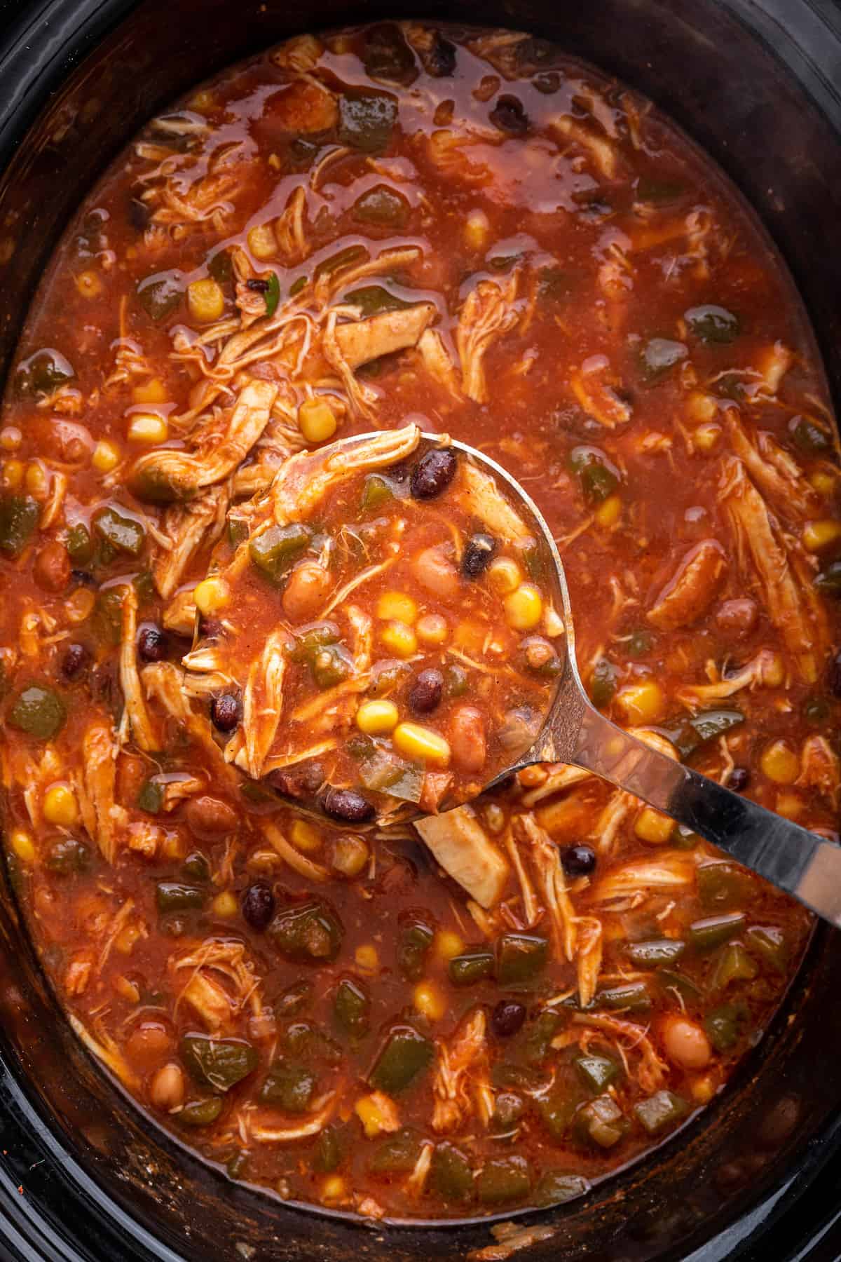 Ladleful of chicken taco soup held over slow cooker