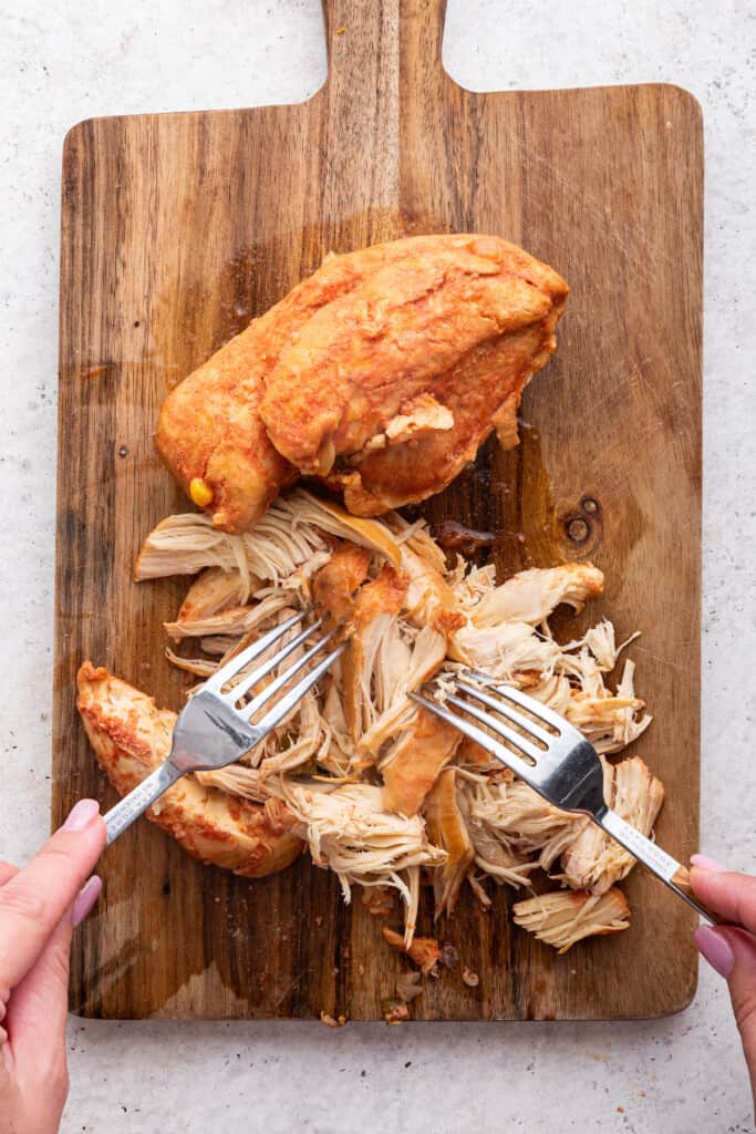 Overhead view showing chicken being shredded with forks