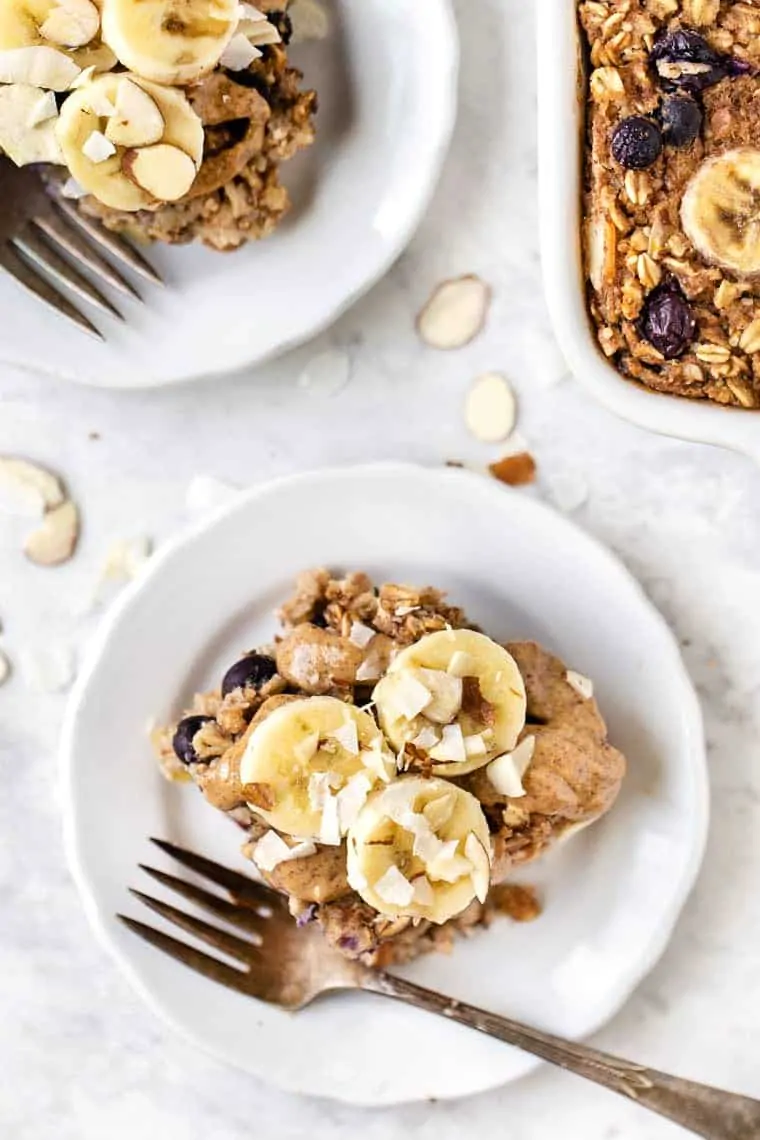 Two plates of healthy baked oatmeal topped with bananas and coconut