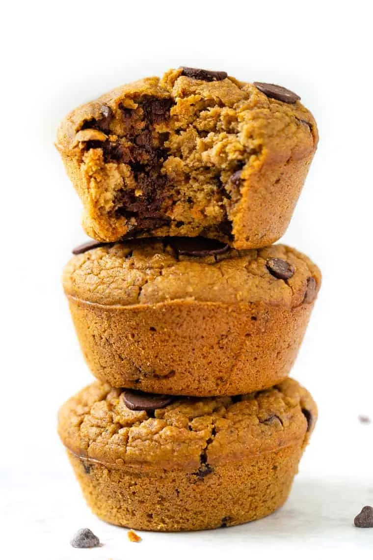 Stack of 3 gluten-free pumpkin chocolate chip muffins, with bite taken out of top