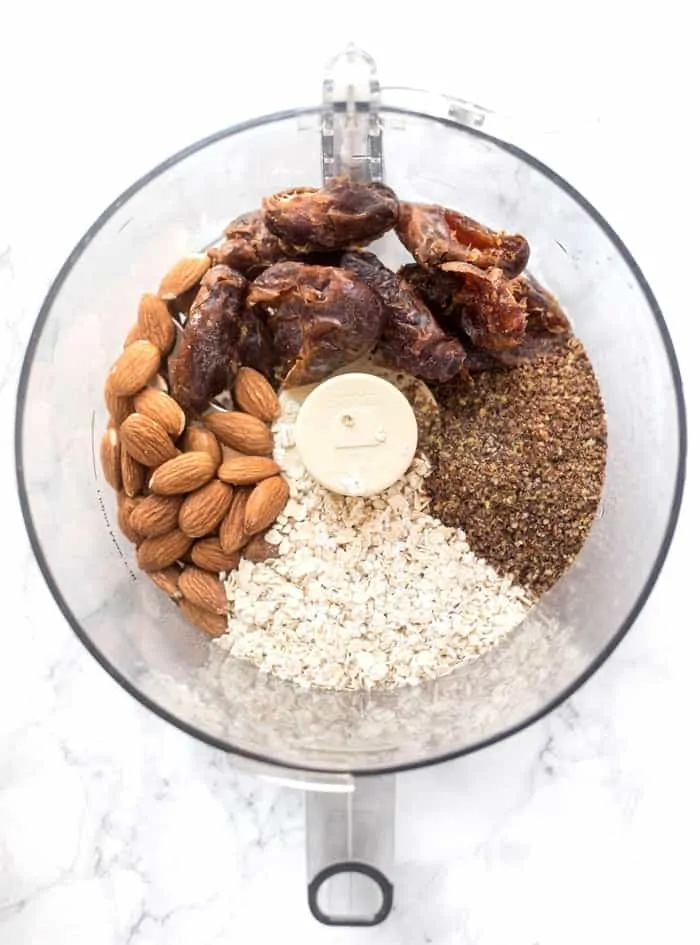 Overhead view of a food processor with dates, almost, oats, and seasonings